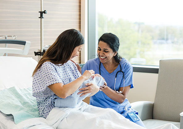 Midwife talking to new mother in hospital a day after delivery. 