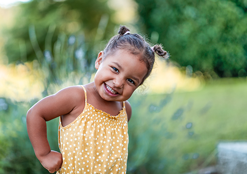 A little girl with her hands on her hips and smiling