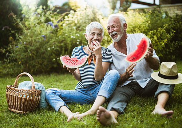 older couple eating watermelon on the lawn